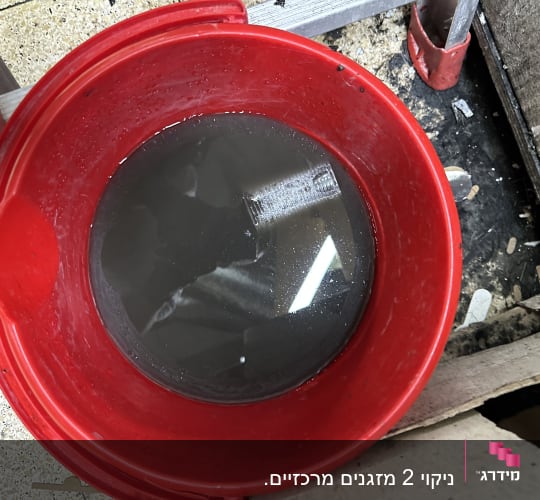 דלי אדום עם מים מלוכלכים על רצפה